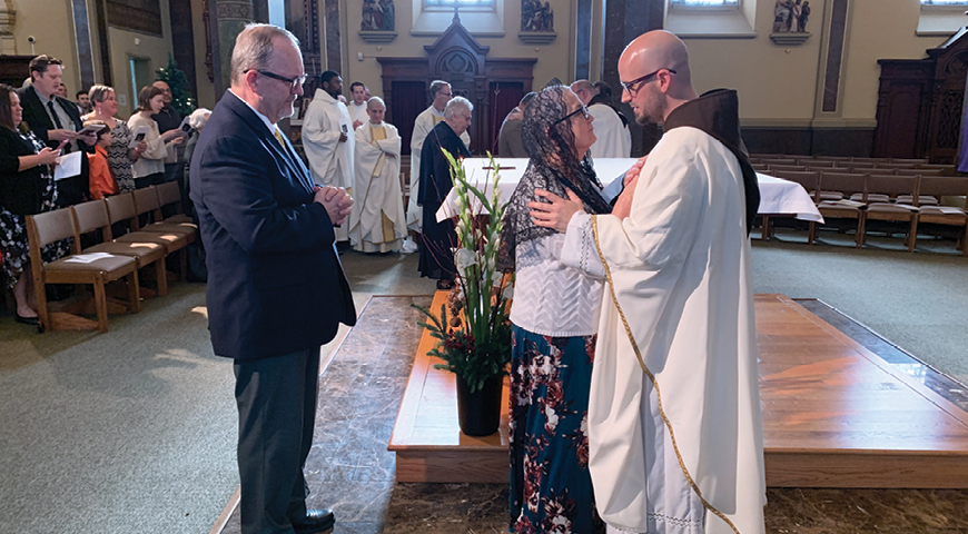 The newly ordained Father M.J. Groark performs his first priestly blessing upon his mother, Anna.