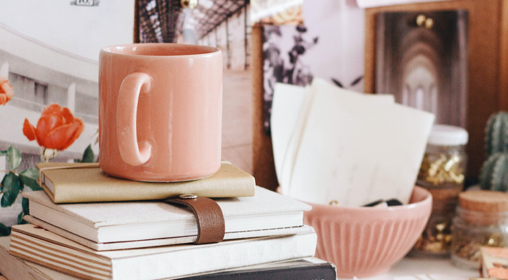 Desk with clutter and pink mug