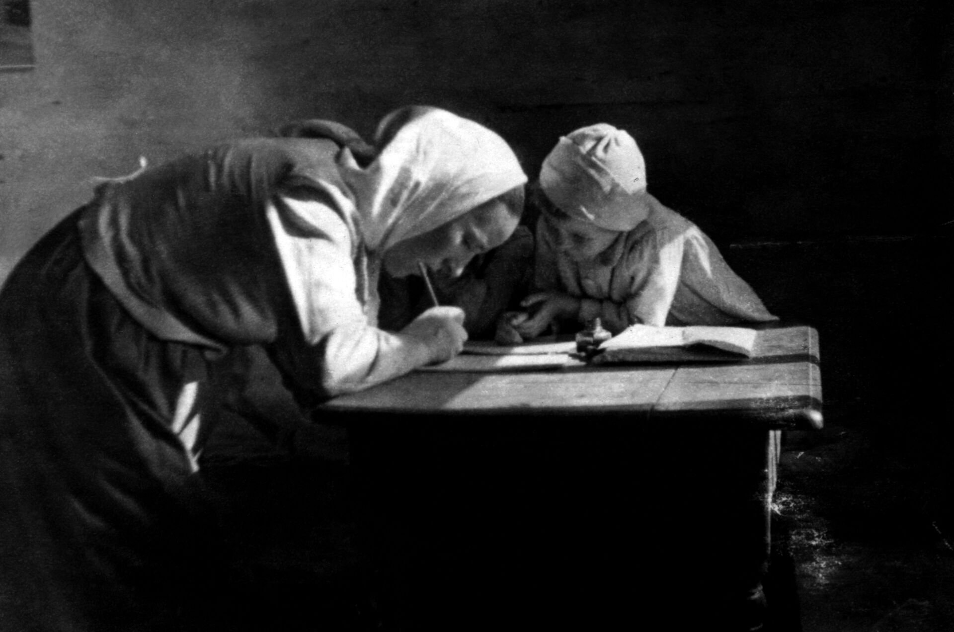 Wiktoria Ulma is pictured writing at a table with her oldest daughter, Stasia. Józef and Wiktoria Ulma secretly gave shelter to eight Jews for almost two years in German-occupied Poland, hiding them from the murderous Nazi regime during the Second World War. The Ulmas are on the path to beatification with the Vatican declaring them martyrs Dec. 17, 2022. The Nazis killed the family and the Jews they were sheltering early in the morning March 24, 1944, right before Easter. (OSV NEWS photo/courtesy Polish Institute of National Remembrance)
