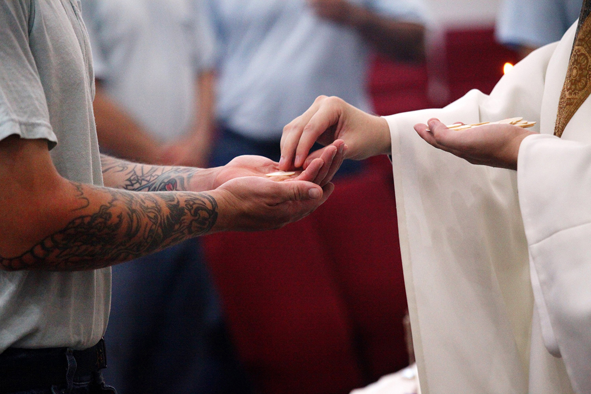 A file photo shows an inmate receiving Communion at the Ellsworth Correctional Facility in Kansas. Catholics involved in prison ministry are trying to bring hope and the light of Christ to those "doing time." (OSV News photo/CNS file, Karen Bonar, The Register)